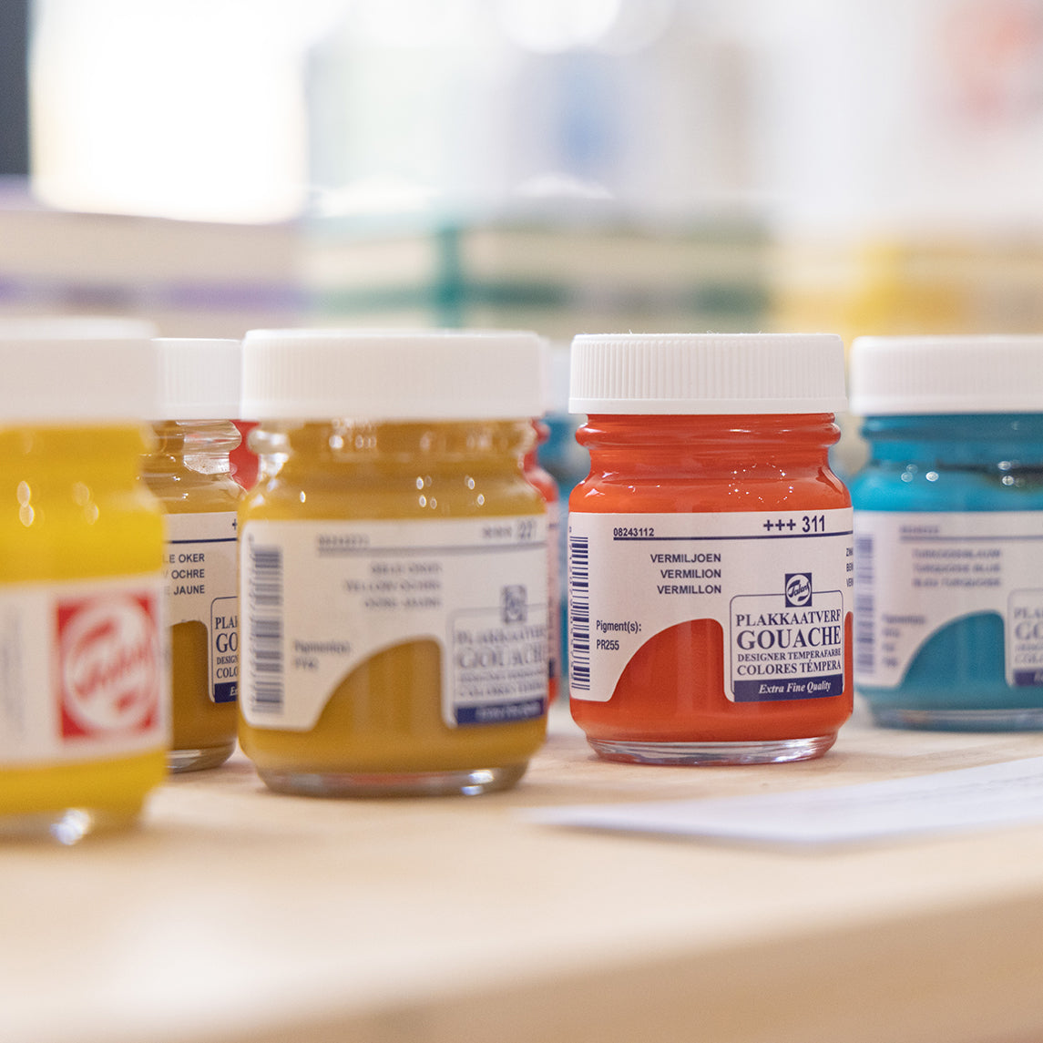 A row of Royal Talens gouache paint jars, including Yellow, Yellow Ochre, Vermillion and Turquoise Blue.