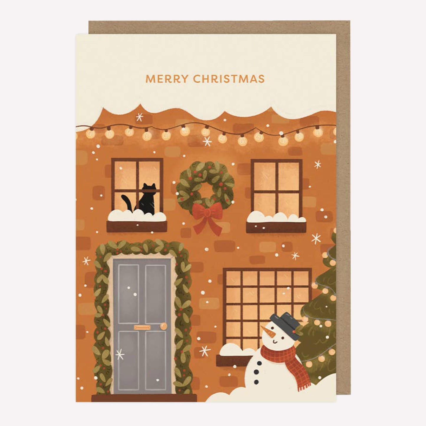 Illustrated Christmas greetings card featuring a snow covered house with a cat in the winodw and a snowman by the door with text reading "Merry Christmas".
