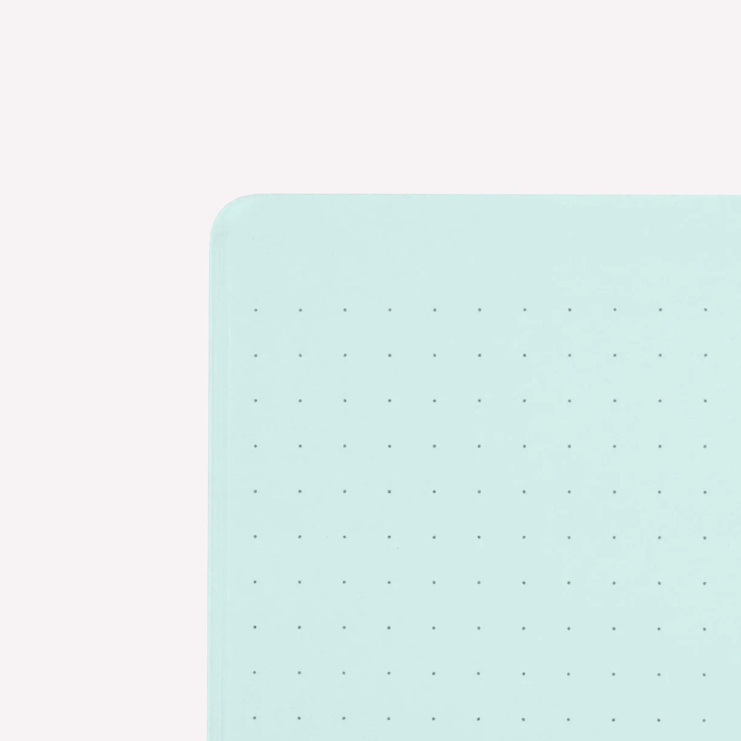 Inside corner of a page of the midori soft cover stapled notebook. Pages are pale blue with a subtle dot grid (5mm spacing).