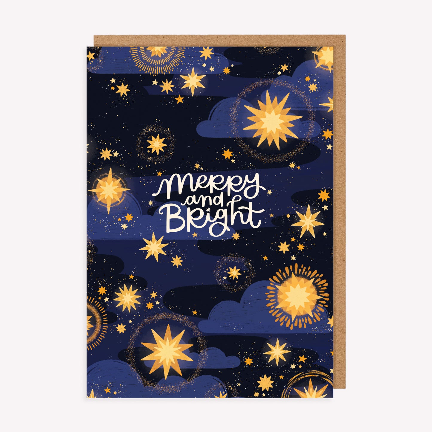 Christmas greetings card with an illustrated pattern of golden stars and handwritten text reading 'Merry and Bright', paired with a kraft envelope.
