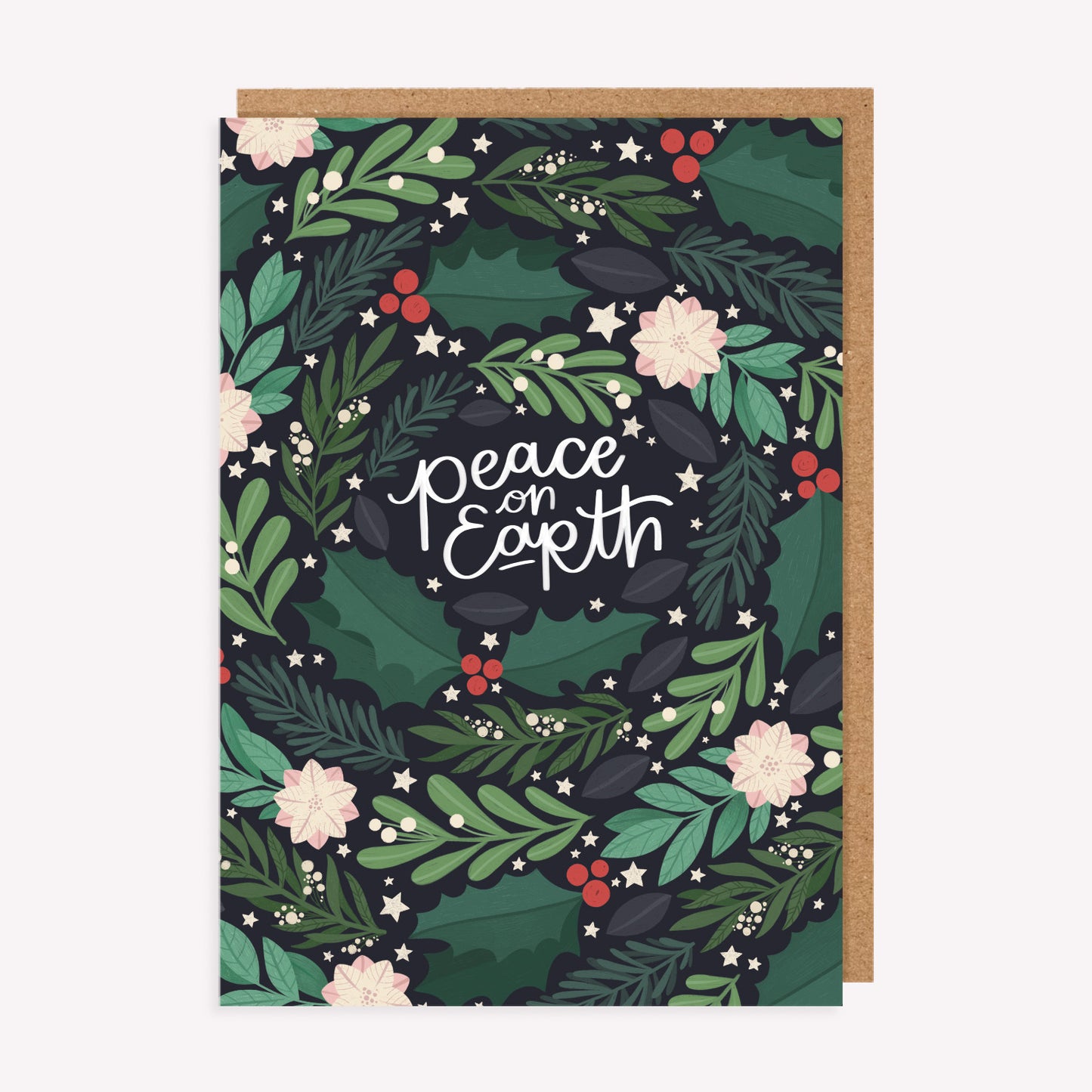 Christmas greetings card with a pattern of winter foliage and handwritten text reading 'peace on earth', paired with a kraft envelope.