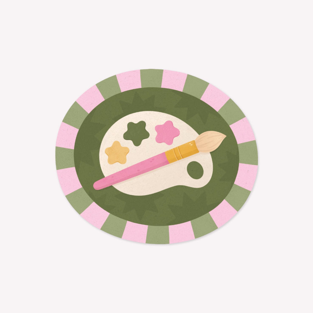 Illustrated oval-shaped sticker featuring a paint palette and a paintbrush, surrounded by a green and pink striped border.