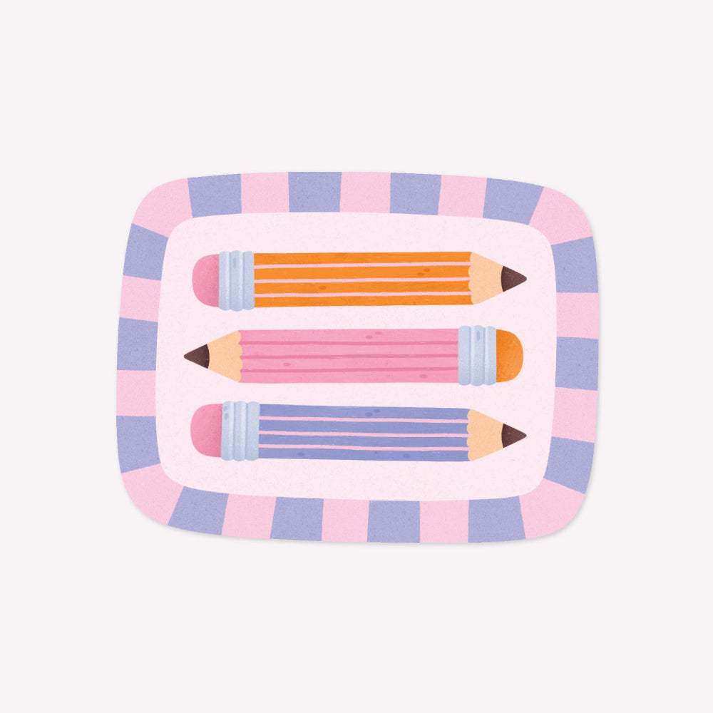 Illustrated sticker featuring three colourful pencils (orange, blue, and pink) arranged horizontally within a striped, square-shaped frame.