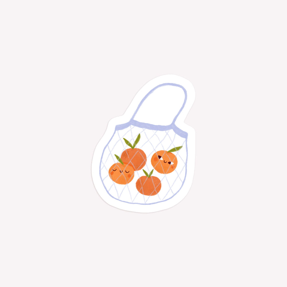 Illustrated die-cut paper sticker of a net shopping bag with several oranges inside.