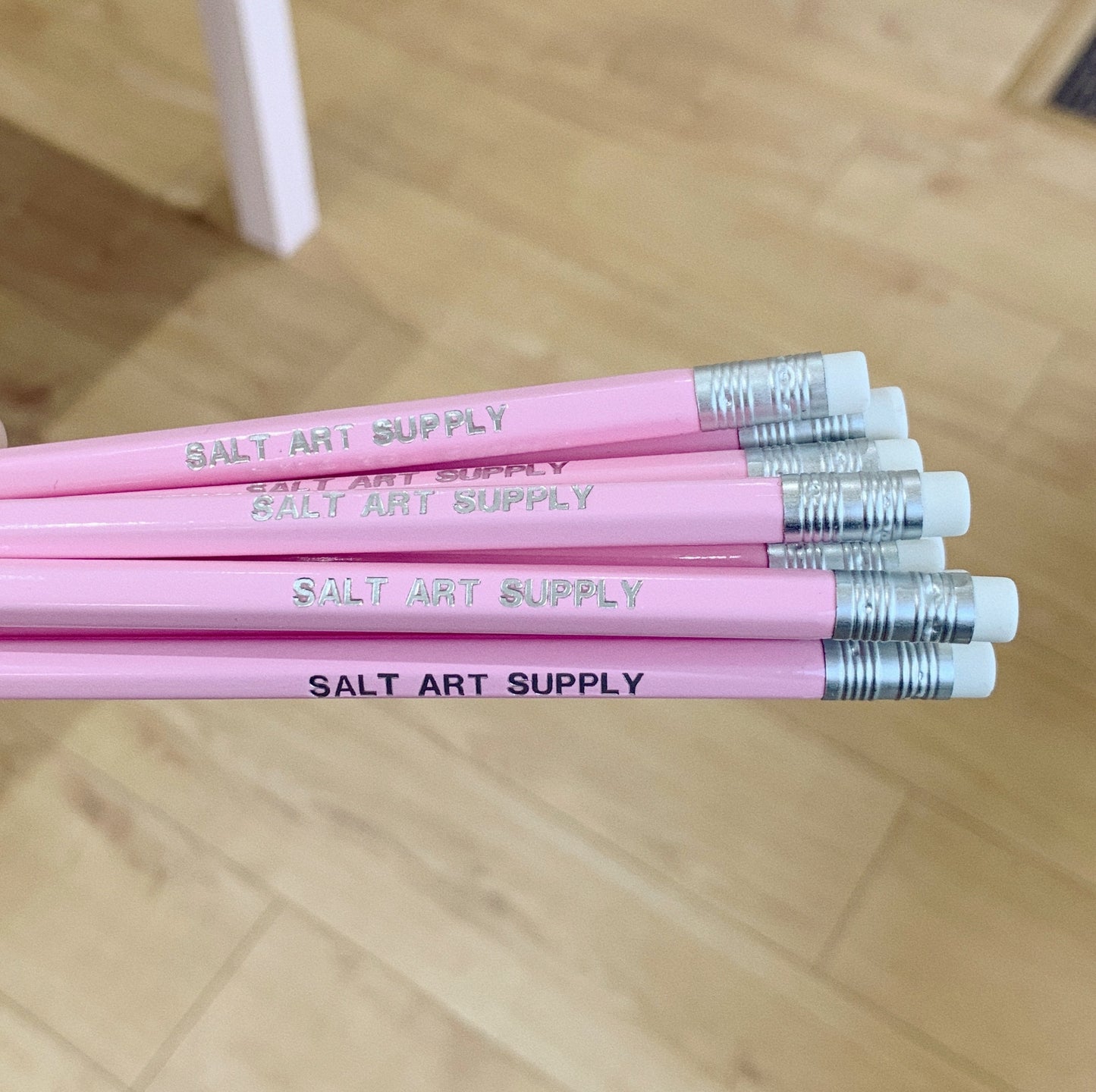 a handful of HB pencil with pink barrells, silver ferrule, white eraser and silver foiled text reading "Salt Art Supply".