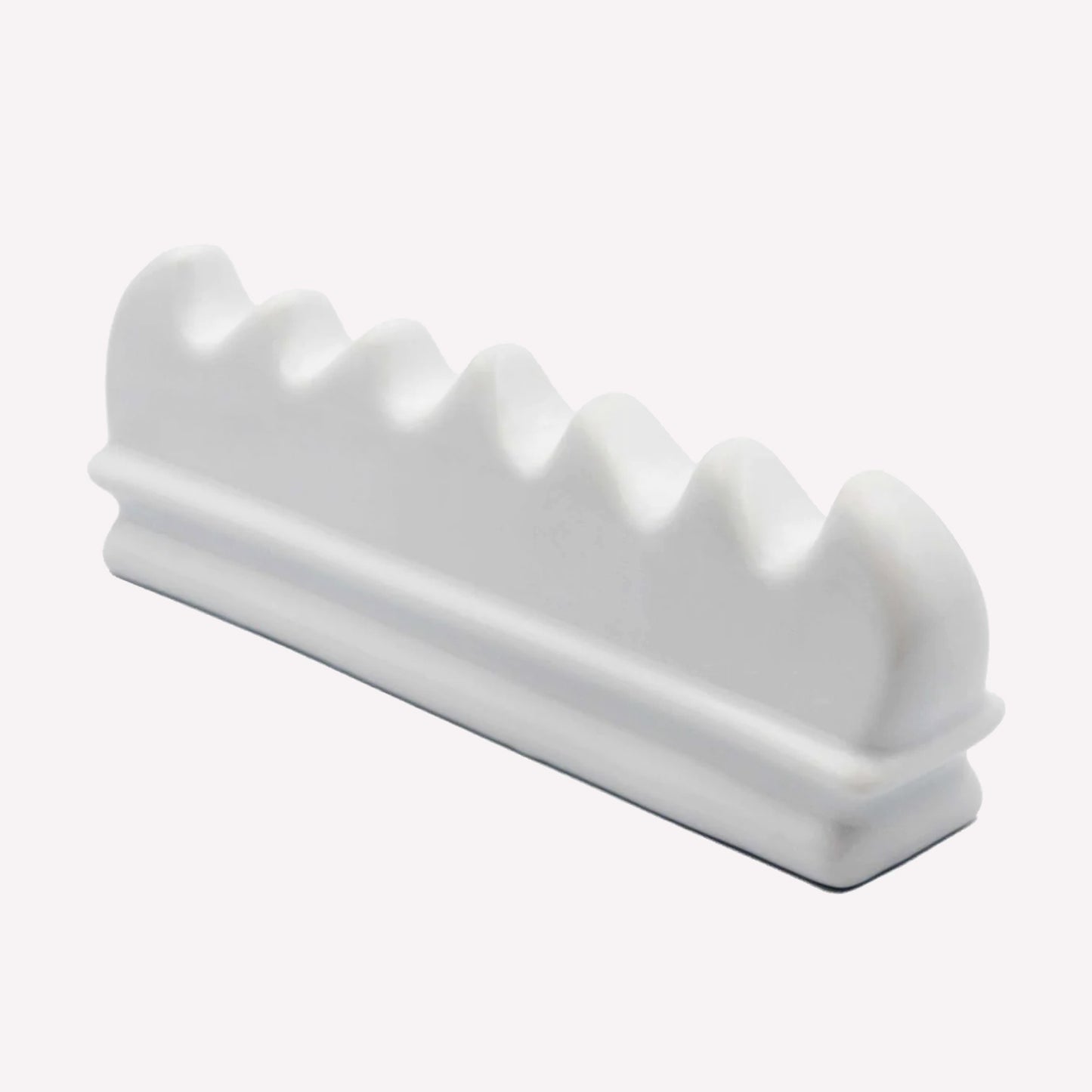 Side view of our ceramic brush rest with 6 spaces to hold paintbrushes of varying sizes and diameters.