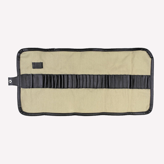 Natural canvas pencil and brush wrap made from cream coloured material with a brown strap, unrolled to display room to store tools and art materials.