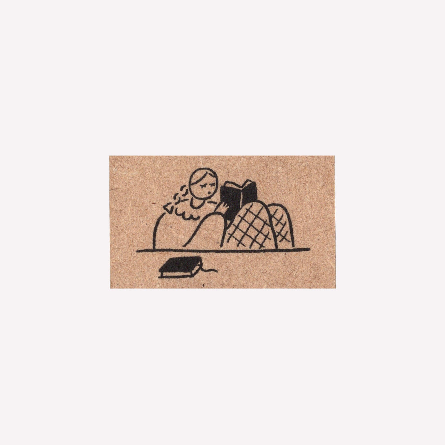 Rubber journalling stamp with a design of a girl reading a book.