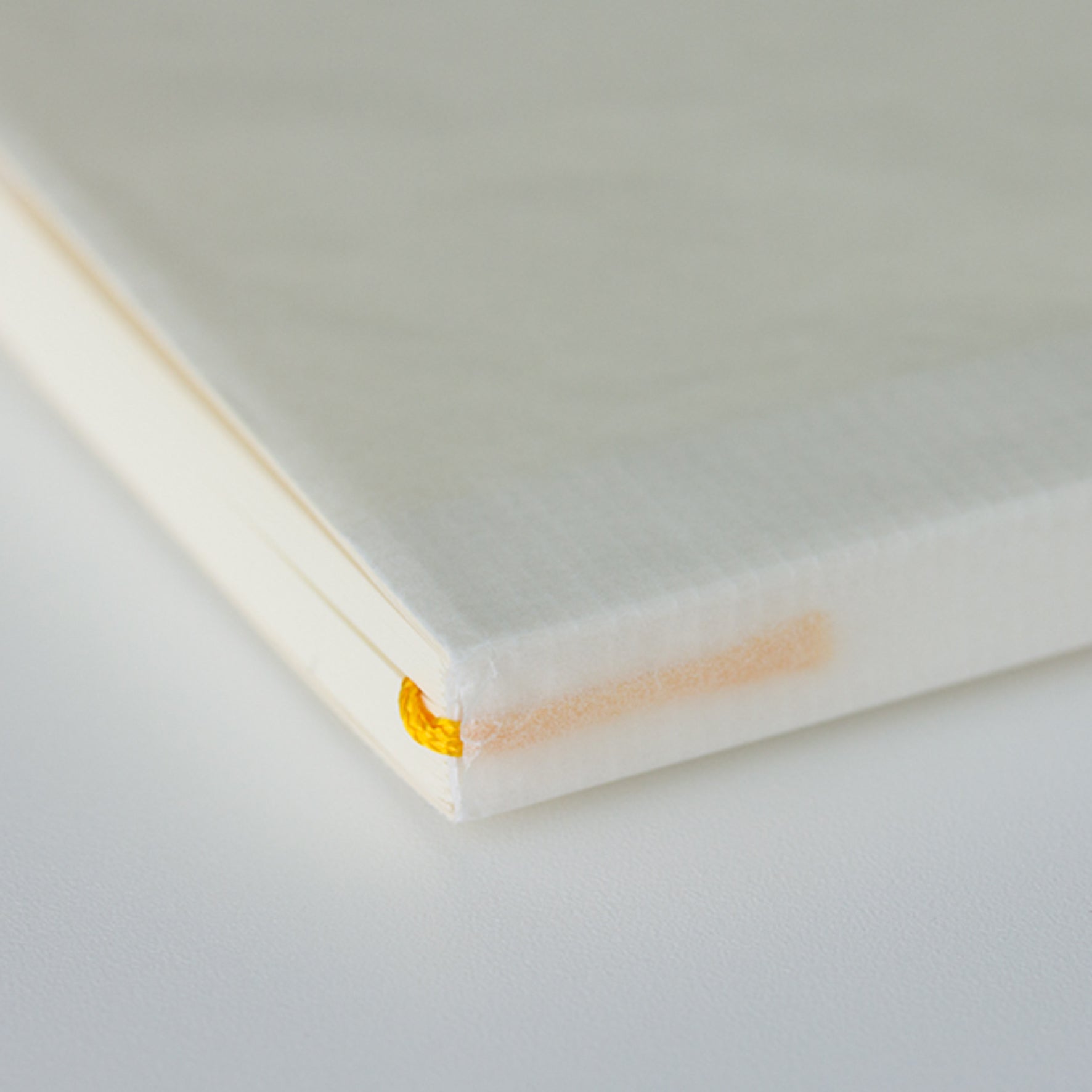MD paper A5 notebook with minimalist cover an exposed thread spine lying flat on a table. 
