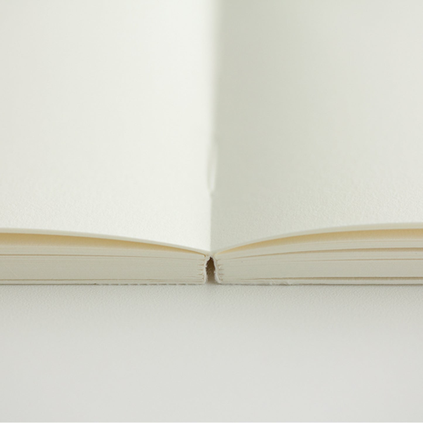 MD paper A7 notebook open flat on a table to show blank pages. 