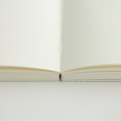 MD paper A7 notebook open flat on a table to show blank pages. 