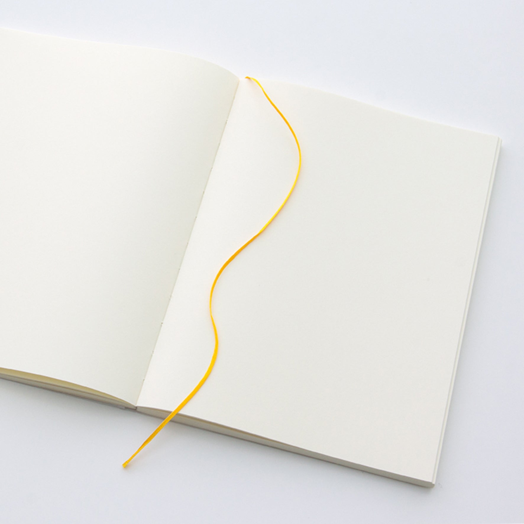 MD Paper A5 notebook open flat on a table to show the ribbon page marker. 