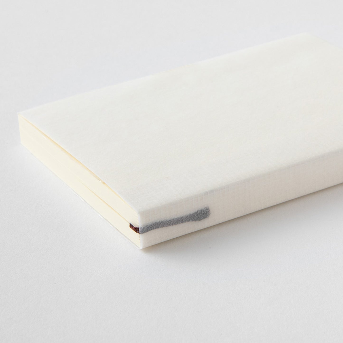 MD paper A7 notebook with minimalist cover an exposed thread spine lying flat on a table. 