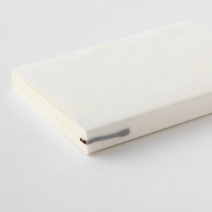 MD paper A7 notebook with minimalist cover an exposed thread spine lying flat on a table. 