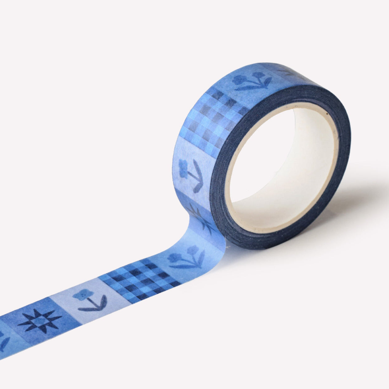 Roll of paper washi tape designed by Claire Paul, featuring a navy blue pattern of flowers and stars.