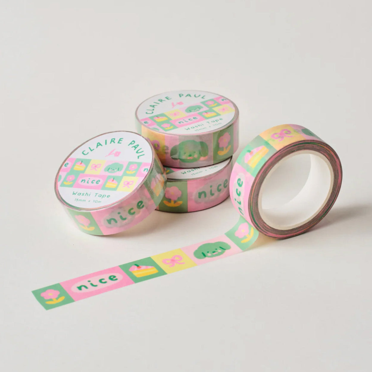 Several paper washi tapes by Claire Paul, all featuring a pattern of charms and trinkets in bright green, pink and yellow colours.
