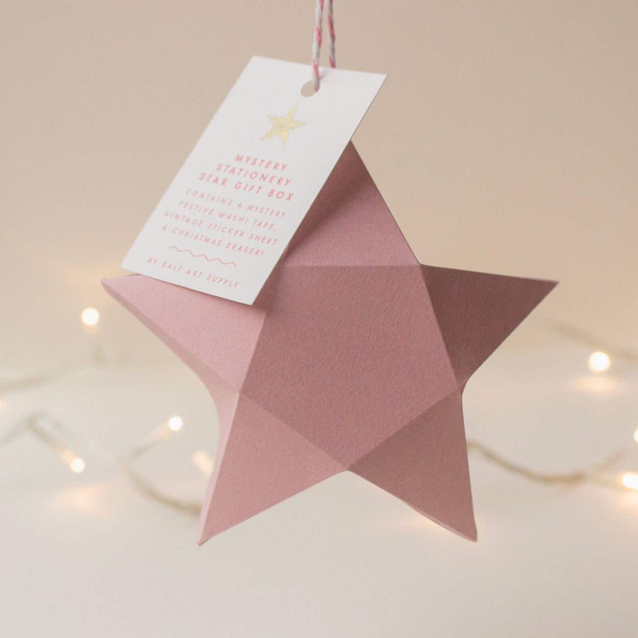 Pink star-shaped gift box with a white gift tag, containing Salt Art Supply's mystery festive stationery gifts.