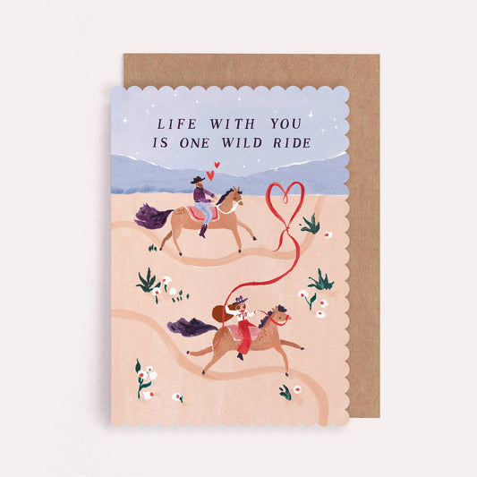 A Valentines greetings card by Sister Paper Co with an illustration of two people on horseback and text that reads "Life With You Is One Wild Ride".