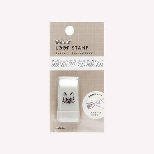 Matoka Deco Loop Stamp of cats faces, packaged with a grid background. 