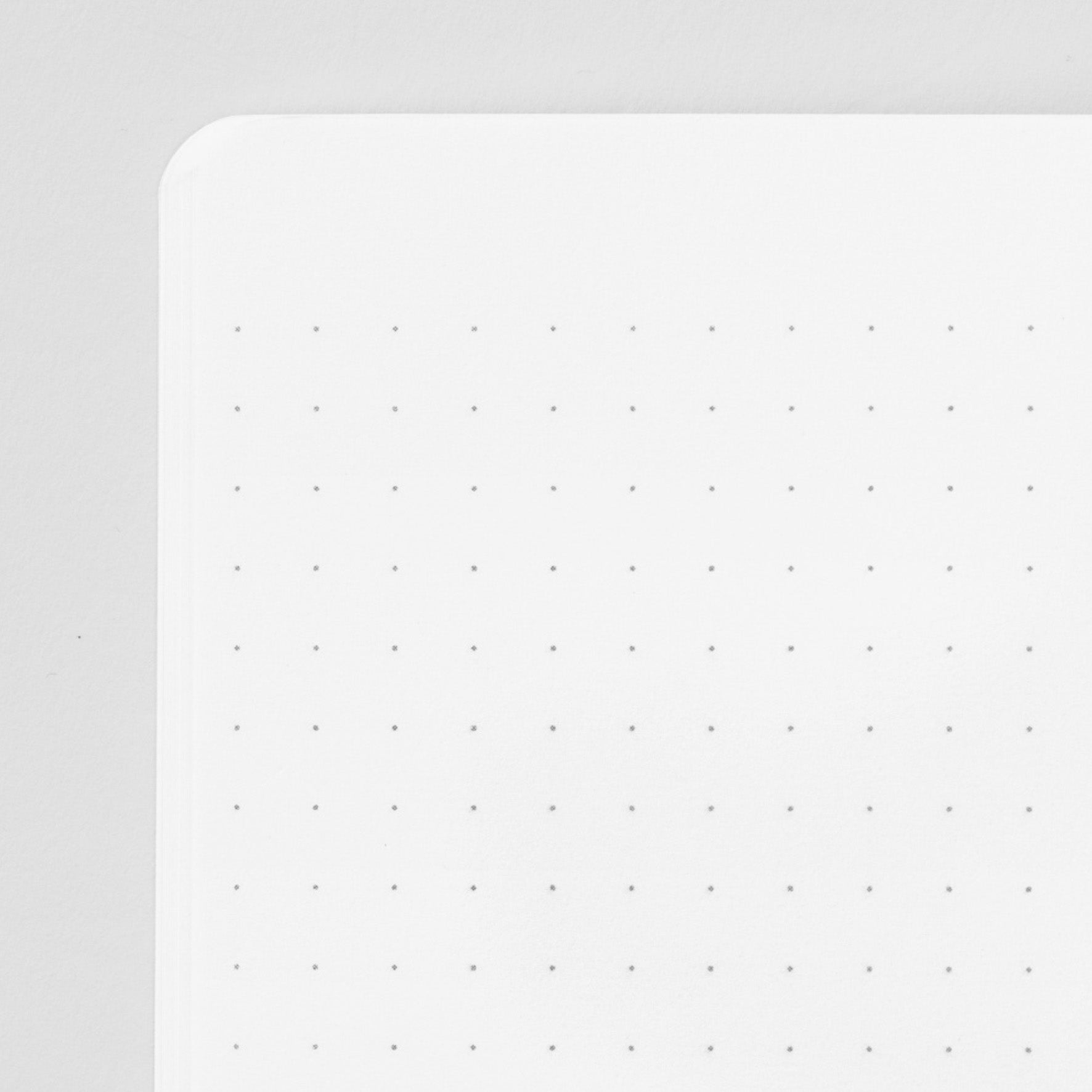 Inside corner of a page of the midori soft cover stapled notebook. Pages are white with a subtle dot grid (5mm spacing). 