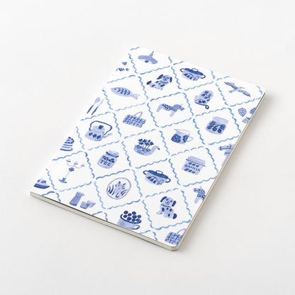 Midori Blue Nordic Yuru Log notebook with a pattern of scandinavian motifs on the cover, lying flat on the a white table. 