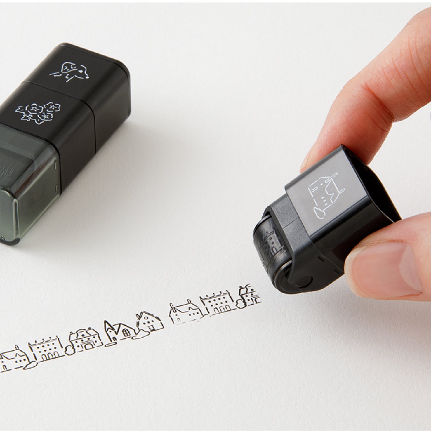 Set of 3 Midori paintable ink roller stamp, featuring dog, floral and building skyline designs, with one stamp in use. 