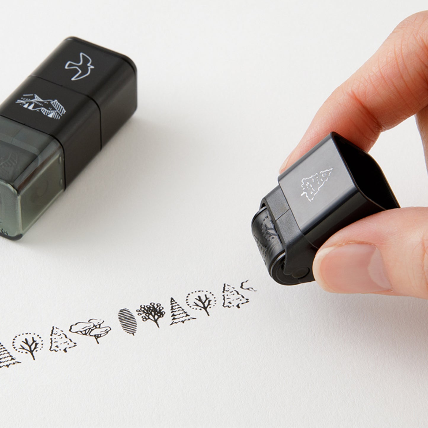 Set of 3 Midori paintable ink roller stamp, featuring mountain, tree and bird designs, with one stamp in use. 