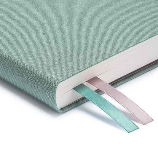 A close up of the corner of Ohh Deer's sage blue daily planner, showing the quality of the linen-style fabric and the two divider ribbons.
