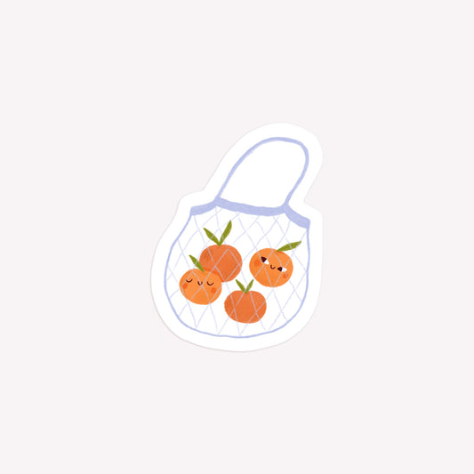 Illustrated die-cut paper sticker of a net shopping bag with several oranges inside.