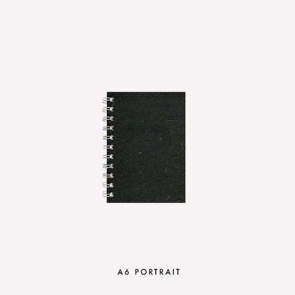 A6 wire bound portrait sketchbook made in the UK by Pink Pig with an ebony coloured banana tissue paper cover and strudy grey board backing.