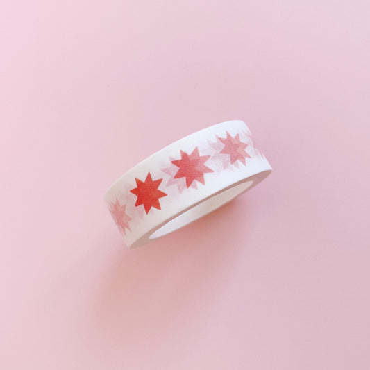 Single roll of paper washi tape, featuring a repeating pattern of pink stars.