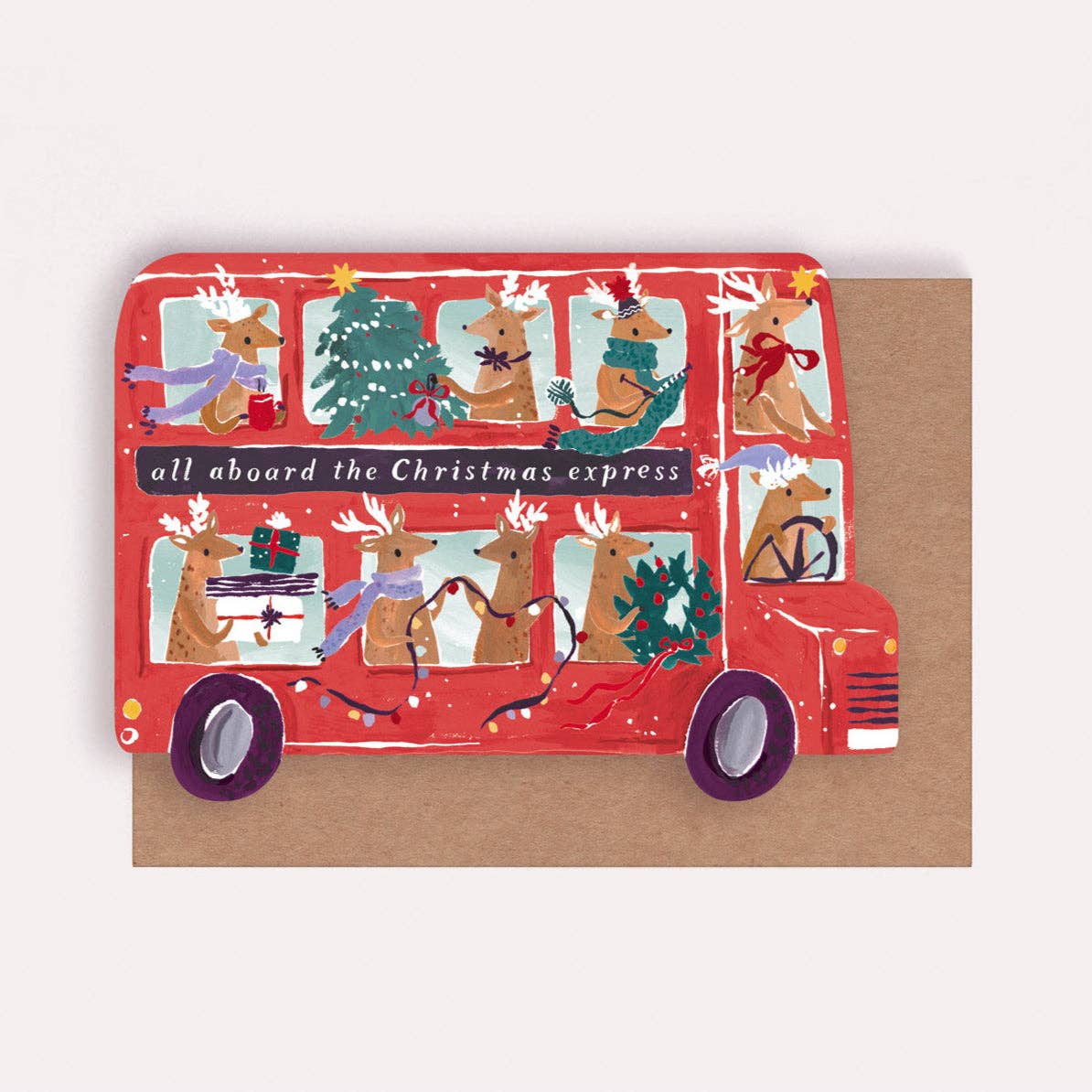 An illustrated Christmas card by Sister Paper Co in the shape of a red bus, with reindeers taking part in various Christmas decorating tasks in the windows and text that reads "All Aboard The Christmas Express".