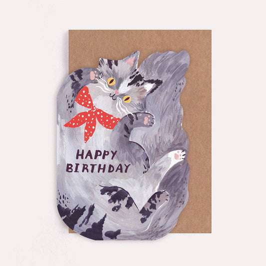 Illustrated die cut greetings card shaped like a fluffy grey cat wearing a red bandana, with text reading 'Happy Birthday'. 