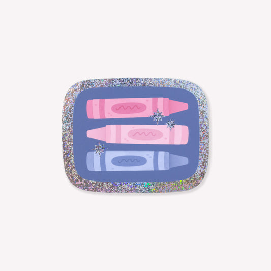 Sparkly sticker with an illustration of three crayons on a blue background with a glittery outline and star details. 