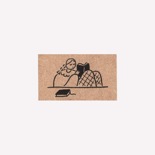 Rubber journalling stamp with a design of a girl reading a book. 