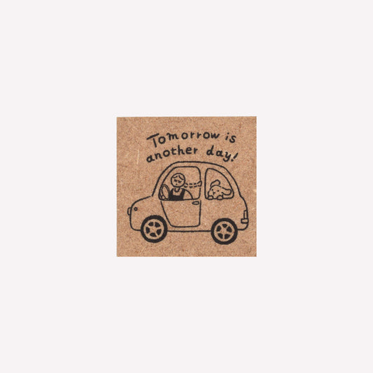 Rubber journalling stamp with a design of a girl and bunny in a car and text reading "tomorrow is another day". 
