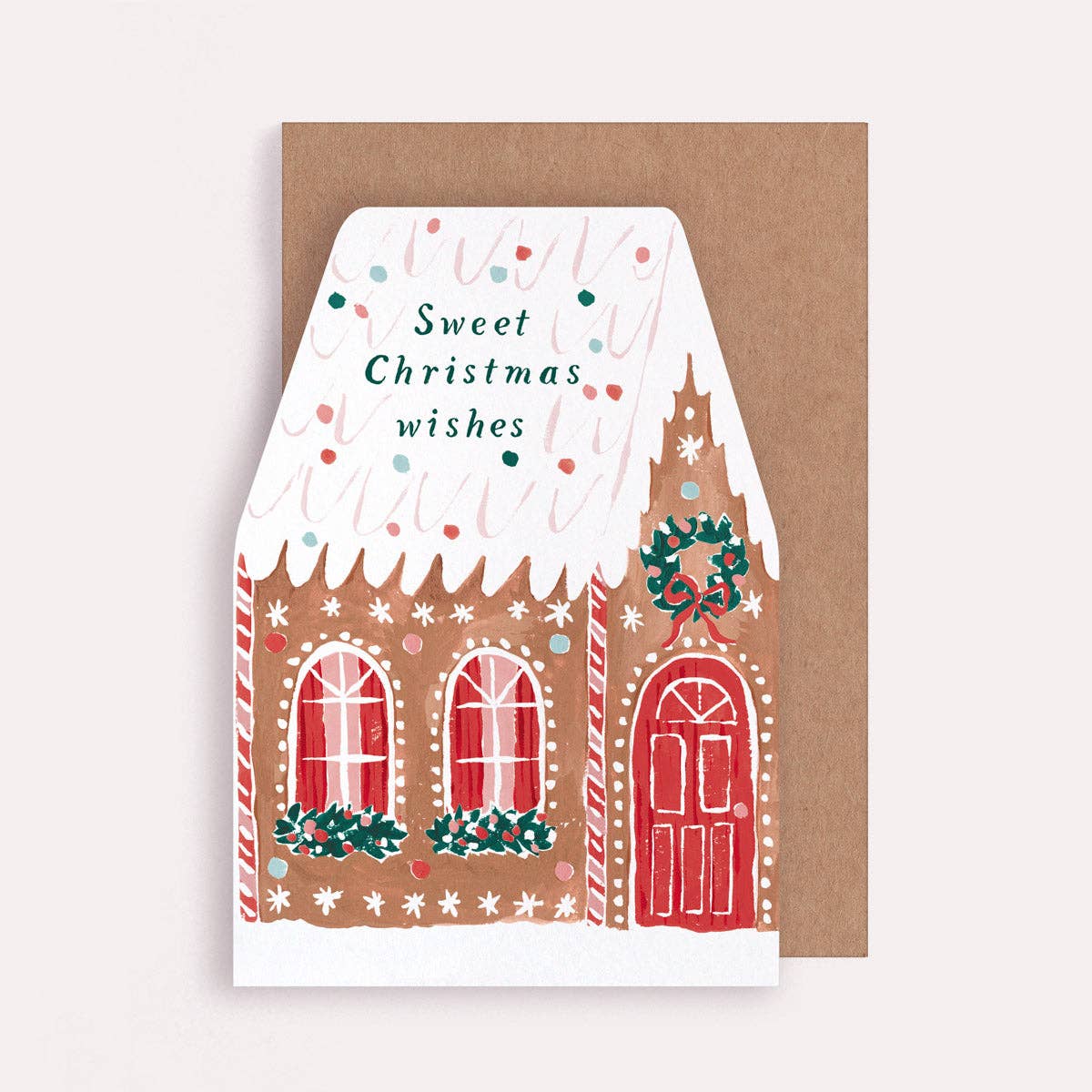 An illustrated Christmas card by Sister Paper Co in the shape of a decorated gingerbread house, with text that reads "Sweet Christmas Wishes".