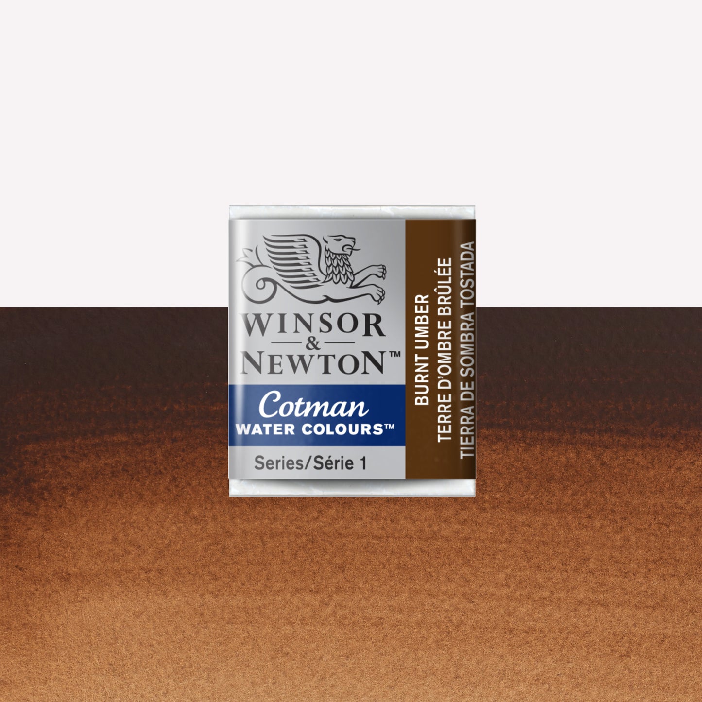 Winsor & Newton Cotman watercolour half pan in the shade Burnt Umber over a vibrant colour swatch. These half pans have a solid formula and are packaged in compressed paint cake. 