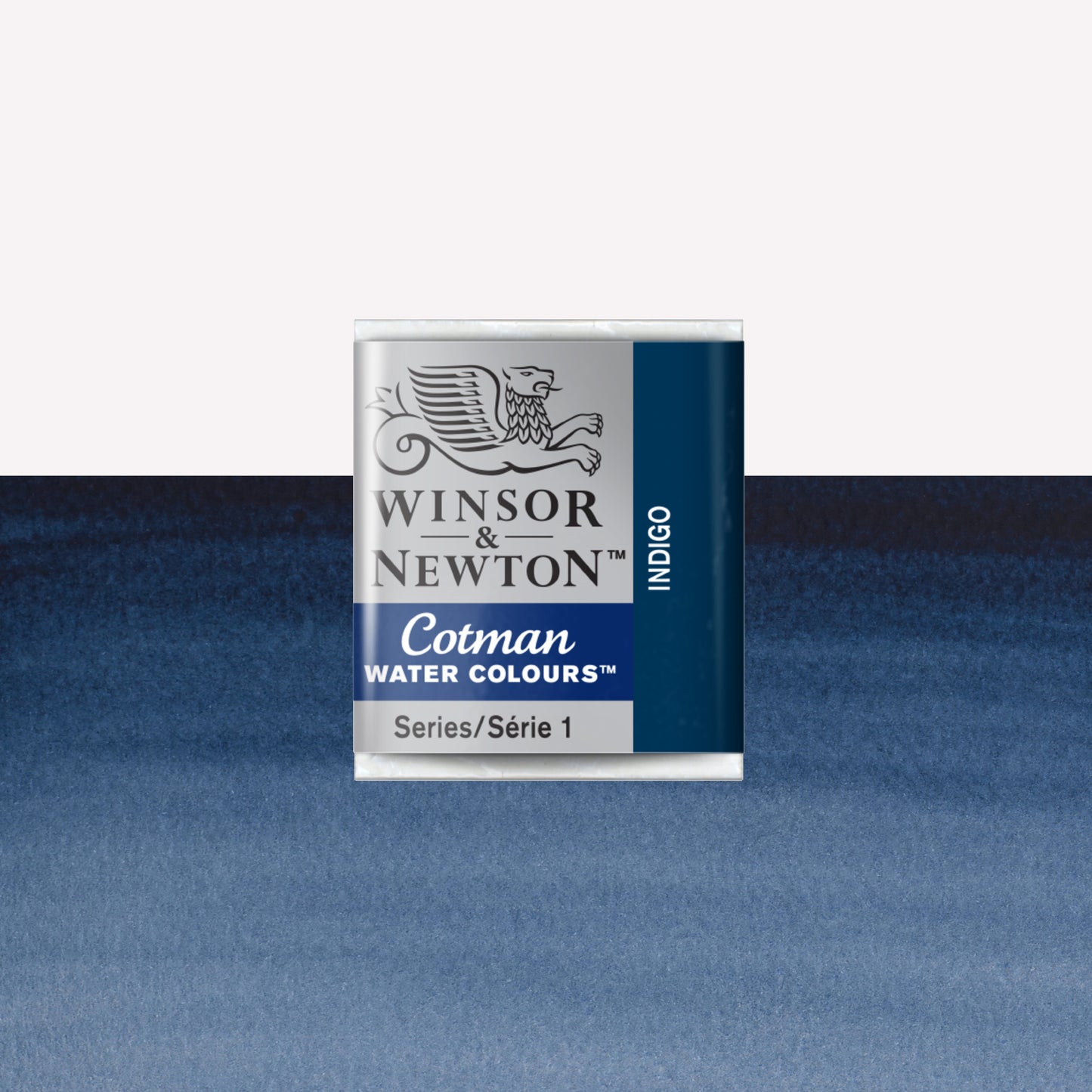Winsor & Newton Cotman watercolour half pan in the shade Indigo over a vibrant colour swatch. These half pans have a solid formula and are packaged in compressed paint cake. 