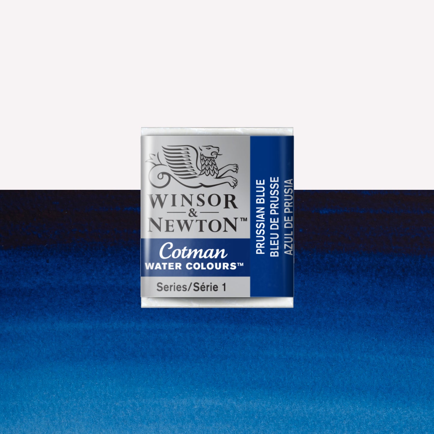 Winsor & Newton Cotman watercolour half pan in the shade Prussian Blue over a vibrant colour swatch. These half pans have a solid formula and are packaged in compressed paint cake. 