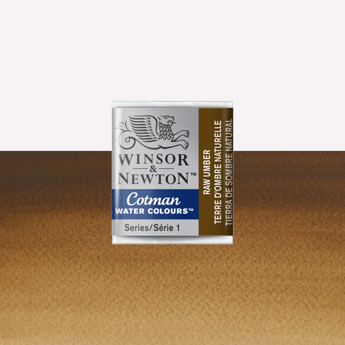 Winsor & Newton Cotman watercolour half pan in the shade Raw Umber over a vibrant colour swatch. These half pans have a solid formula and are packaged in compressed paint cake. 