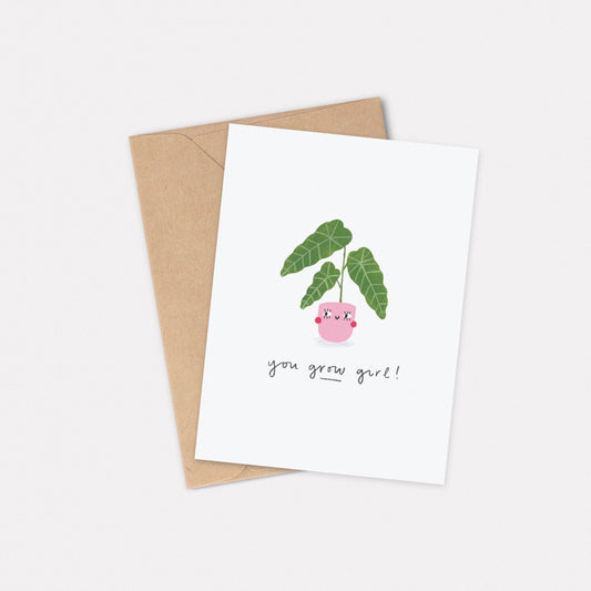 An A6 illustrated card featuring a house plant in a pink pot with a smiley face on it. The text underneath reads “You Grow Girl!”. Behind the card is a kraft brown envelope.